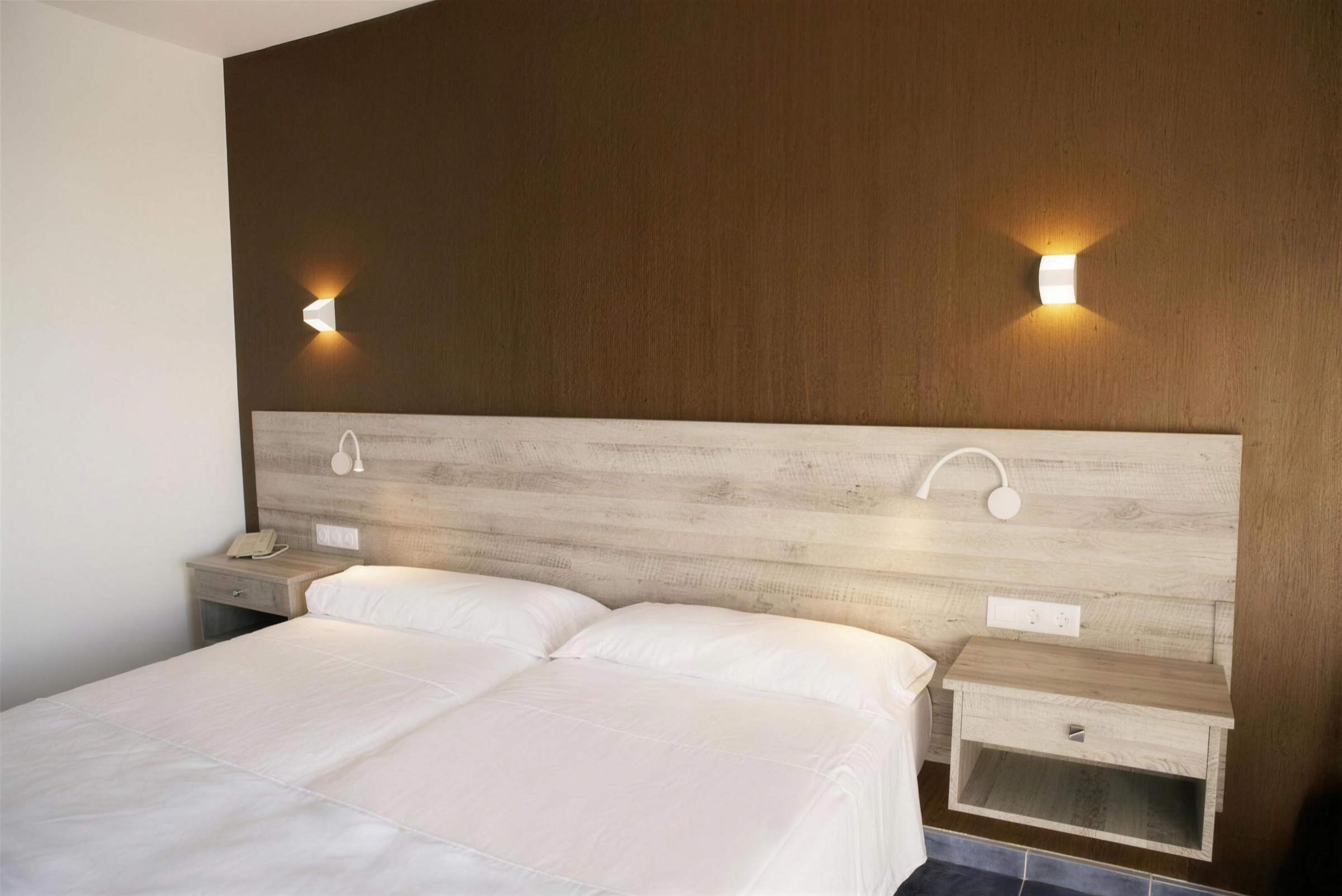 Chambre d'hôtel avec tête de lit rénovée en bois clair
